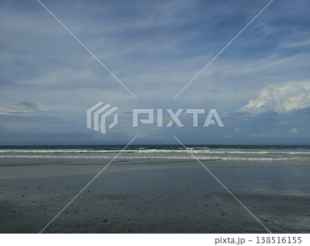 Serene landscape view of an empty Andaman beach featuring wet, reflective sand and gentle rolling waves under a calm, cloudy sky. Serene landscape view of an empty Andaman beach featuring wet, reflective sand and gentle rolling waves under a calm, cloudy sky. 138516155