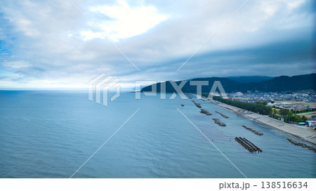 早春の富山県東部、小川の河口周辺からの眺め、雲に隠れている北アルプスや洋上風力発電風車たちの様子 138516634