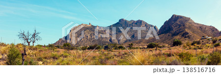Panoramic view of mountain ridge and valley with dirt road on a sunny day Panoramic view of mountain ridge and valley with dirt road on a sunny day 138516716