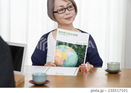 海外旅行保険の契約書に署名捺印するシニア女性 海外旅行保険の契約書に署名捺印するシニア女性 138517101