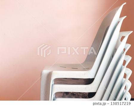 Stacked Plastic Chairs Against Light Background Stacked Plastic Chairs Against Light Background 138517219