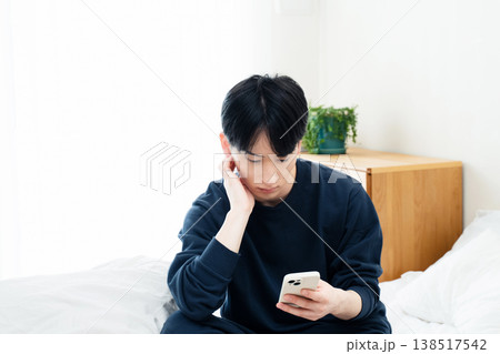 ベッドでスマホを見る若い男性 138517542