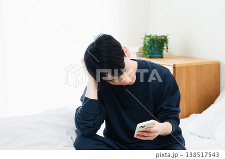 ベッドでスマホを見る若い男性 138517543