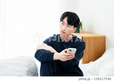 ベッドでスマホを見る若い男性 138517546