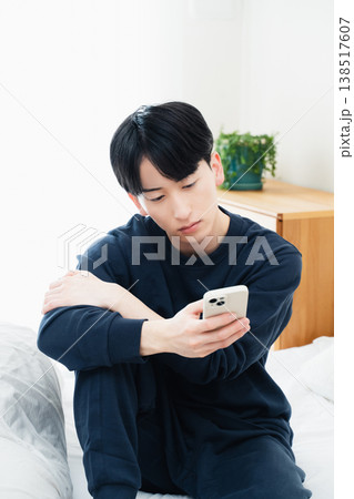ベッドでスマホを見る若い男性 138517607