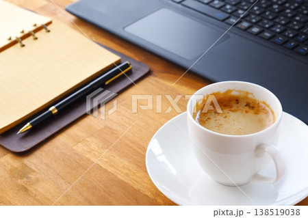 淹れたての美味しいコーヒー、カフェ・ラッテを飲みながらノートパソコンでデスクワークをしているイメージ 138519038