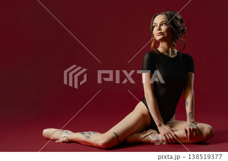 Tattooed Ballerina in a Black Leotard Sitting on a Red Background 138519377