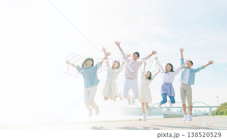 青空の下で大ジャンプ！笑顔で飛び跳ねる若い男女グループ 138520529