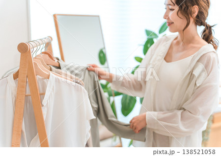 ハンガーラックから洋服を選ぶアジア人女性（衣装合わせ,コーディネート,着替え,身支度） 138521058