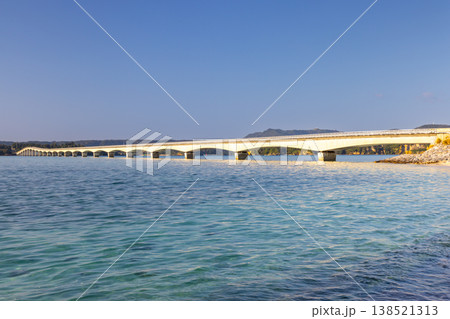 沖縄県国頭郡今帰仁村 古宇利島のビーチから朝の古宇利大橋と古宇利ブルーの海 沖縄県国頭郡今帰仁村 古宇利島のビーチから朝の古宇利大橋と古宇利ブルーの海 138521313