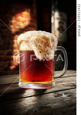 Foamy ruby beer in a pint glass, on a rustic wooden bar background, conveying a concept of refreshment Foamy ruby beer in a pint glass, on a rustic wooden bar background, conveying a concept of refreshment 138521412