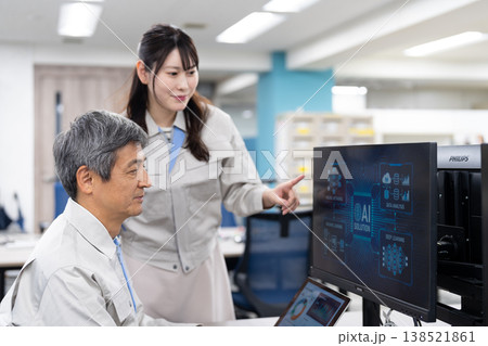 パソコンの画面を見ながら打ち合わせをする作業着の男女 パソコンの画面を見ながら打ち合わせをする作業着の男女 138521861