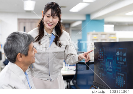 パソコンの画面を見ながら打ち合わせをする作業着の男女 パソコンの画面を見ながら打ち合わせをする作業着の男女 138521864