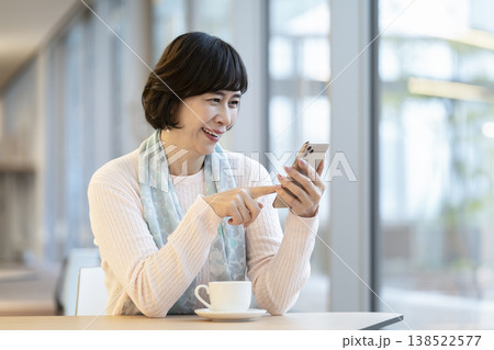 カフェのテーブル席でスマートフォンを操作する60代の女性 カフェのテーブル席でスマートフォンを操作する60代の女性 138522577