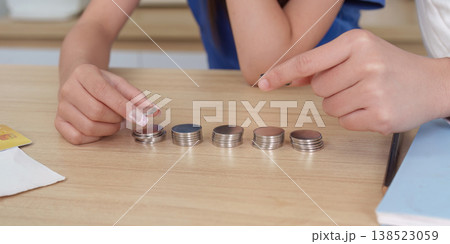 Hands arranging coins on a wooden table 138523059