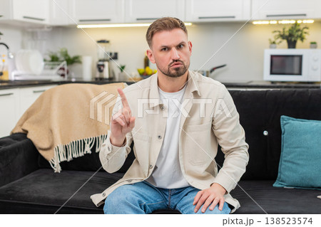 Young man waves finger no no at camera shows firm refusal and disagree sign with serious calm face Young man waves finger no no at camera shows firm refusal and disagree sign with serious calm face 138523574