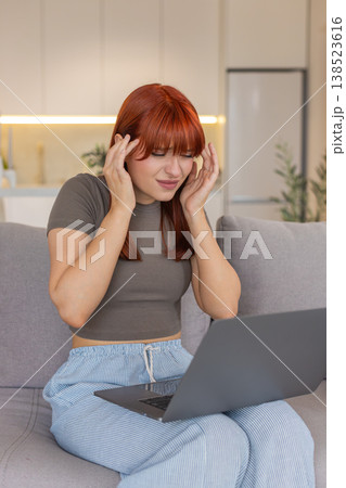 Young woman with laptop rubs temples headache pause closes eyes tired takes break for relief needed Young woman with laptop rubs temples headache pause closes eyes tired takes break for relief needed 138523616