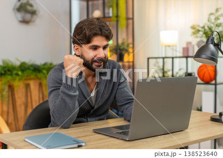Indian happy man submits project on laptop hits submit smiles fist pump celebrates victory good news Indian happy man submits project on laptop hits submit smiles fist pump celebrates victory good news 138523640