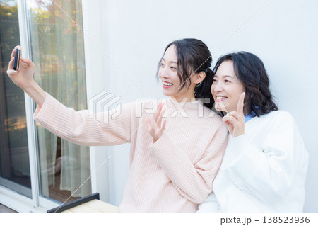 縁側でスマホ自撮りする仲良し母娘のポートレート 縁側でスマホ自撮りする仲良し母娘のポートレート 138523936