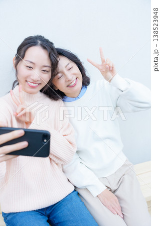 縁側でスマホ自撮りする仲良し母娘のポートレート 138523948