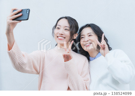 レトロ感のある縁側でスマホ自撮りする仲良し母娘のポートレート 138524099