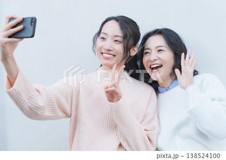 レトロ感のある縁側でスマホ自撮りする仲良し母娘のポートレート レトロ感のある縁側でスマホ自撮りする仲良し母娘のポートレート 138524100
