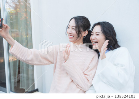 レトロ感のある縁側でスマホ自撮りする仲良し母娘のポートレート レトロ感のある縁側でスマホ自撮りする仲良し母娘のポートレート 138524103