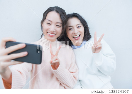 レトロ感のある縁側でスマホ自撮りする仲良し母娘のポートレート レトロ感のある縁側でスマホ自撮りする仲良し母娘のポートレート 138524107