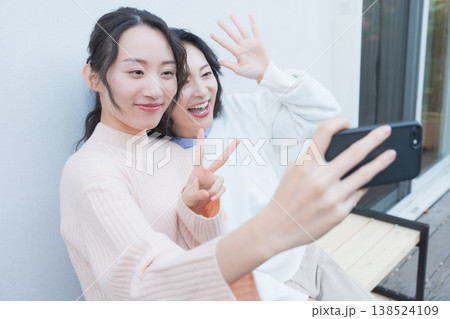 レトロ感のある縁側でスマホ自撮りする仲良し母娘のポートレート レトロ感のある縁側でスマホ自撮りする仲良し母娘のポートレート 138524109