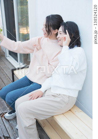 レトロ感のある縁側でスマホ自撮りする仲良し母娘のポートレート レトロ感のある縁側でスマホ自撮りする仲良し母娘のポートレート 138524120