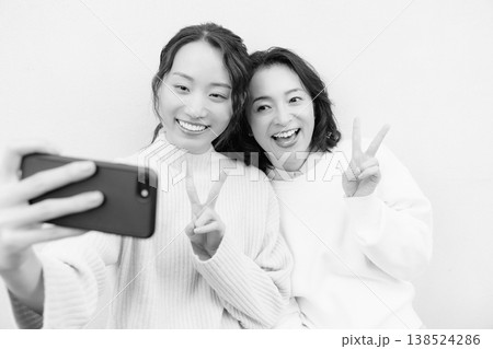 縁側でスマホ自撮りする仲良し母娘のモノクロポートレート 138524286