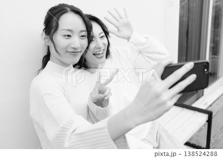 縁側でスマホ自撮りする仲良し母娘のモノクロポートレート 138524288