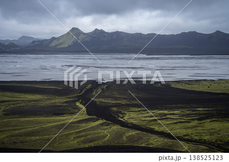 Mountainous volcanic landscape with huge glacial river and heavy clouds above, Iceland Mountainous volcanic landscape with huge glacial river and heavy clouds above, Iceland 138525123