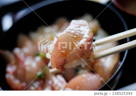 ローカルスーパーに併設された食堂のミックス漬丼の切り身をハシで持つ ローカルスーパーに併設された食堂のミックス漬丼の切り身をハシで持つ 138525393
