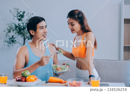A happy couple prepares fresh vegetables, laughing and enjoying cooking a healthy meal together. A happy couple prepares fresh vegetables, laughing and enjoying cooking a healthy meal together. 138526259