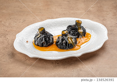 Black khinkali dumplings with sauce on plate 138526391