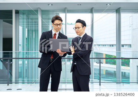 オフィスビルでノートパソコンを見ながら打ち合わせをする二人の日本人ビジネスマン 138526400