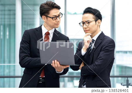 オフィスでパソコンを見ながら真剣に話し合う二人のビジネスマン 138526401