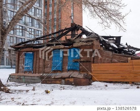 Old wooden house with shutters against modern high rise buildings covered in snow cold early spring urban contrast cityscape and winter atmosphere. Old wooden house with shutters against modern high rise buildings covered in snow cold early spring urban contrast cityscape and winter atmosphere. 138526578