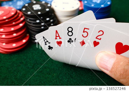 Hand holding 1 Pair combination poker playing cards with colorful casino chips on green felt table gambling Hand holding 1 Pair combination poker playing cards with colorful casino chips on green felt table gambling 138527246