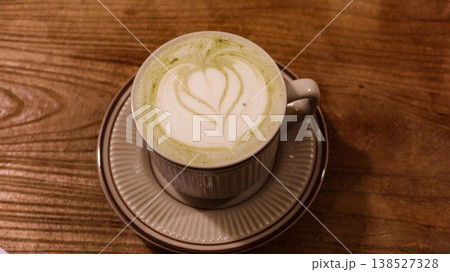 close up of green tea latte coffee with coffee art and foam on top in a mug in classic Japanese style on a wooden table with copyspace close up of green tea latte coffee with coffee art and foam on top in a mug in classic Japanese style on a wooden table with copyspace 138527328