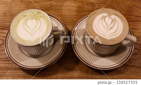 close up of a hojicha latte coffee and a green tea latte with coffee art and foam on top in a mug in classic Japanese style on a wooden table with copyspace close up of a hojicha latte coffee and a green tea latte with coffee art and foam on top in a mug in classic Japanese style on a wooden table with copyspace 138527355