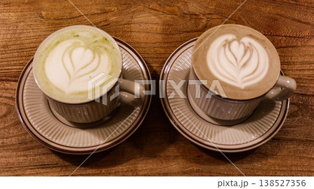 close up of a hojicha latte coffee and a green tea latte with coffee art and foam on top in a mug in classic Japanese style on a wooden table with copyspace close up of a hojicha latte coffee and a green tea latte with coffee art and foam on top in a mug in classic Japanese style on a wooden table with copyspace 138527356