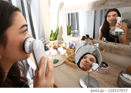Teen Girl Using Facial Radiofrequency Device at Mirror 138527657