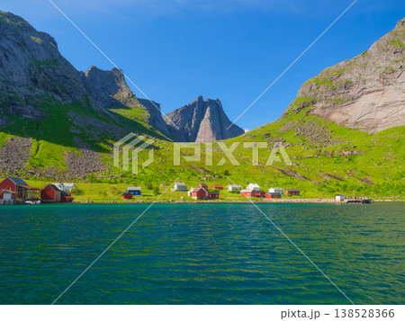 Scenic Norwegian village in Lofoten with mountain reflections in a calm fjord. Scenic Norwegian village in Lofoten with mountain reflections in a calm fjord. 138528366