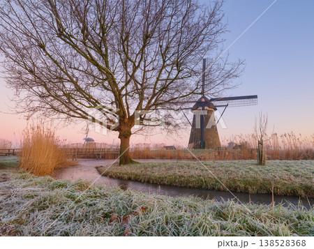 Traditional Dutch windmill at sunrise with frost on grass and trees. Scenic Holland landscape 138528368