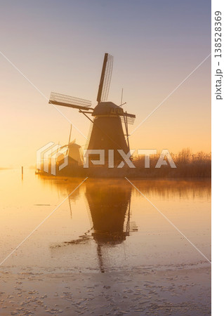 Scenic landscape of windmill in the Netherlands during a foggy golden hour. Scenic landscape of windmill in the Netherlands during a foggy golden hour. 138528369