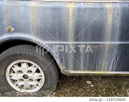 A rusted vintage car being abandoned on a street with flat tires and rusty bodywork 138529660