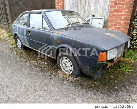 A rusted vintage car being abandoned on a street with flat tires and rusty bodywork 138529665