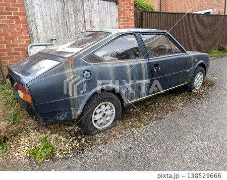 A rusted vintage car being abandoned on a street with flat tires and rusty bodywork A rusted vintage car being abandoned on a street with flat tires and rusty bodywork 138529666